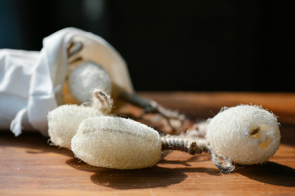 Set of natural eco friendly loofah sponges placed on wooden table in sunlight